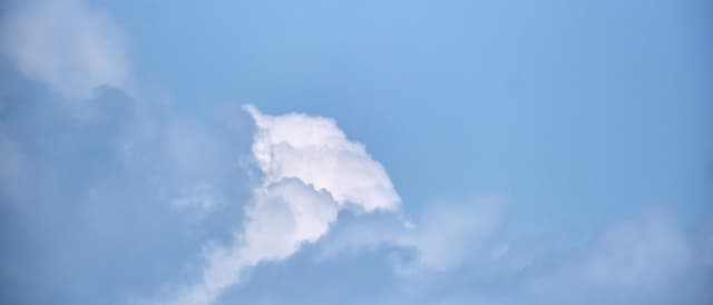 A solitary white cloud formation against a pale blue sky