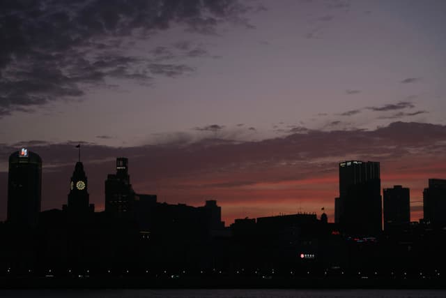 Silhouette of a city skyline against a twilight sky with purple and orange clouds